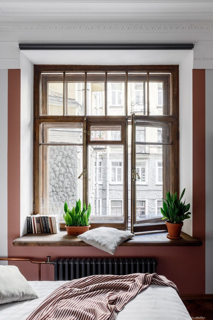 Уютная спальня с большими окнами и растениями